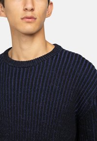 Maglione a coste blu navy con tessuto testurizzato e scollatura a girocollo; presenta righe orizzontali in diverse tonalità di blu.