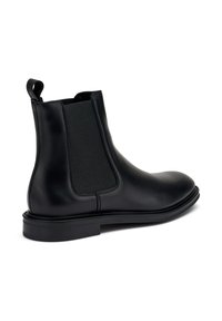 Stivale Chelsea in pelle nera con pannelli elastici laterali, texture liscia, punta rotonda e una linguetta alla caviglia. Suola in gomma piatta.