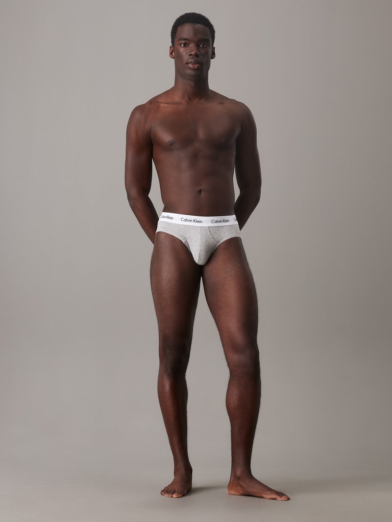 Boxer in grigio di Calvin Klein con cintura bianca, caratterizzati da una vestibilità aderente, morbido tessuto di cotone e design minimalista. Modello in piedi.