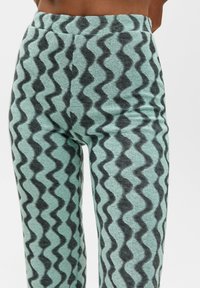 A pair of light turquoise knit pants featuring a zigzag pattern in dark gray. They have an elastic waistband and a soft texture.