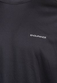 Schwarzes Sportshirt mit kurzen Ärmeln, aus strukturiertem Material und dem Wort "ENDURANCE" in Weiß auf der linken Vorderseite.