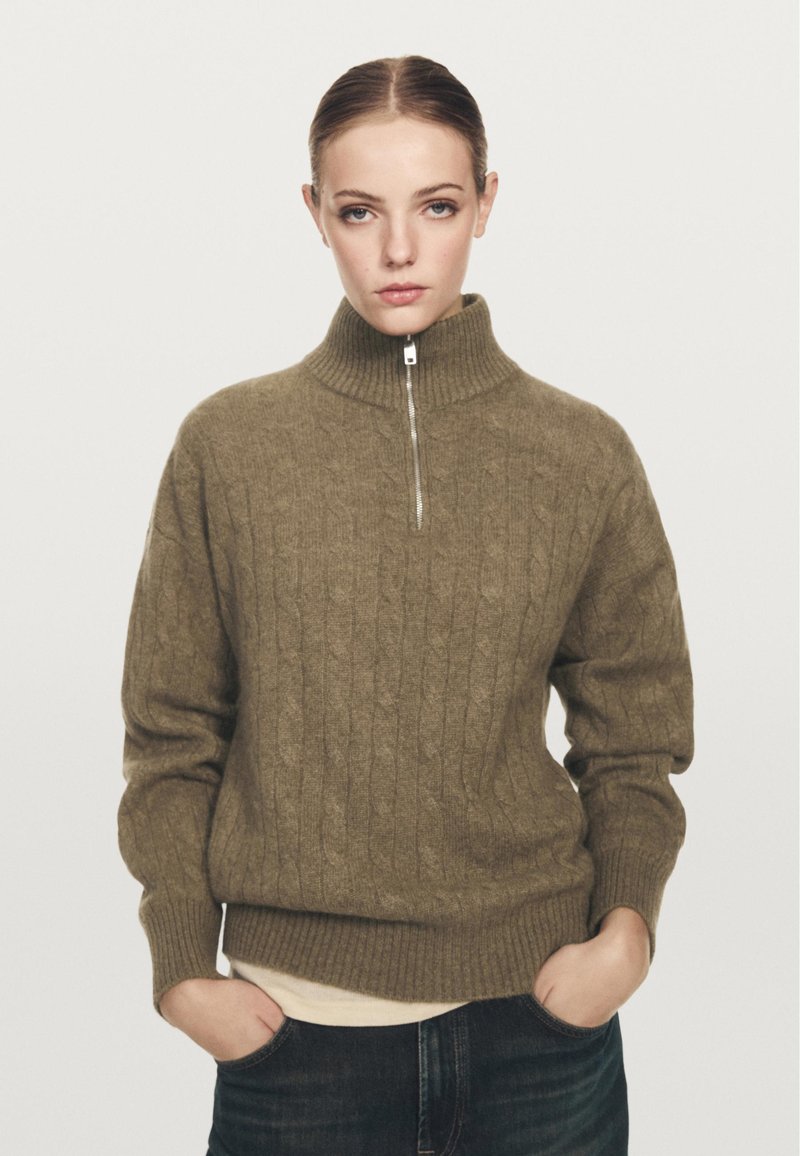 Olijfgroen zip-up trui met een geribde hoge kraag, kabelbreipatroon en lange mouwen. De pasvorm is losjes met een geribde onderkant.