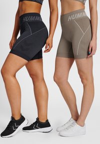 Höga aktiva shorts i svart och beige, med texturerat tyg, randiga mönster och kontrasterande logodetaljer.