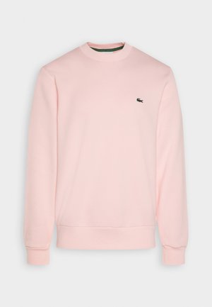 Lyserosa hettegenser laget av mykt stoff, med rund hals og ribbestrikkede mansjetter. Inkluderer en liten grønn Lacoste-logo på brystet.