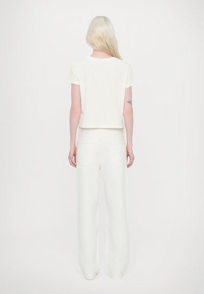 T-shirt blanc court à manches courtes, associé à un pantalon large blanc en tissu doux. Design simple et minimaliste.