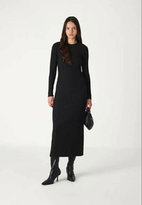 Černé dlouhé šaty s přiléhavým střihem a přímou siluetou, vyrobené z hladkého, elastického materiálu, spárované s černými kozačkami do půli lýtek.