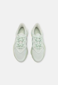 Ljusgröna mesh-sneakers med texturerade accenter, rund tå och platta snören. Dämpad sula med en minimal logotyp på innersulan.