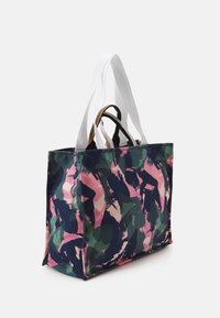 Bolso tote rectangular con un patrón abstracto de pinceladas en rosa, verde y azul marino, que cuenta con dos asas blancas para el hombro y dos asas cortas marrones.