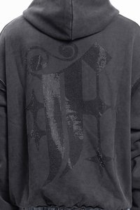 Felpa grigio carbone con un grande design in rhinestone neri sul retro, che include lettere stilizzate e accenti a forma di stella. Tessuto morbido.