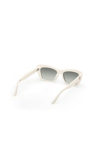 Cream-colored sunglasses with a rounded geometric shape, gray tinted lenses, and smooth plastic frame featuring subtle metallic accents on the hinges.