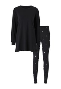 Sort bluse med lange ærmer og sideslids, parret med sorte leggings med hvidt stjernemønster. Blødt materiale, afslappet pasform, enkelt design.