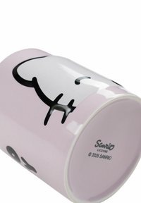 Tazza in ceramica con una finitura lucida di colore rosa pastello, caratterizzata da un design di un personaggio dei cartoni animati nero. Sul fondo è riportato il marchio Sanrio e l'anno 2025.
