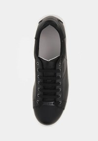 Sneaker in pelle nera con punta arrotondata, suola bianca e lacci neri. Presenta un logo "Guess" argentato sul lato e una texture liscia.