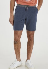 Marinblå shorts i bomullsblandning har en grå snörning i midjan, sidofickor och franskant. Bärs med vita sneakers.