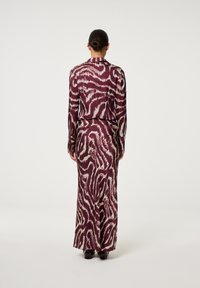 Langes, tailliertes Kleid im burgunderfarbenen und cremefarbenen Tierdruck. Hergestellt aus glattem Stoff, mit langen Ärmeln und gerader Silhouette.