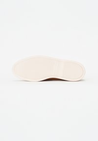 La suela del zapato es blanca con un patrón texturizado, presenta una forma redondeada y una ligera curva hacia la punta. Superficie suave sin marcas.