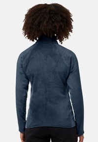 Pullover in pile blu con colletto alto, superficie strutturata e maniche lunghe. Presenta pannelli laterali a contrasto per un ulteriore dettaglio di design.
