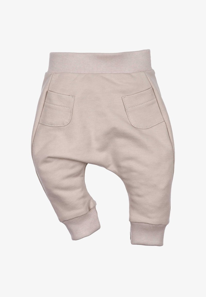 Jogging pantaloni per neonati di un leggero beige con una vita a coste, due tasche frontali e gambe affusolate, realizzati in morbido cotone.