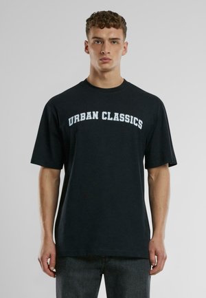 Fekete pamut póló rövid ujjakkal és kerek nyakkivágással. Az elején ívelt betűtípussal fehér szöveg olvasható: "URBAN CLASSICS".