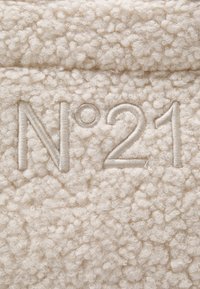 Cream-colored, textured fabric featuring soft loops. The embroidery reads "N°21" in a lighter shade, integrated into the plush surface.