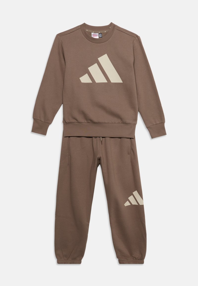 Sweat-shirt marron à manches longues et pantalon de jogging assorti avec logo Adidas beige sur la poitrine et la cuisse gauche, posé à plat sur fond blanc.