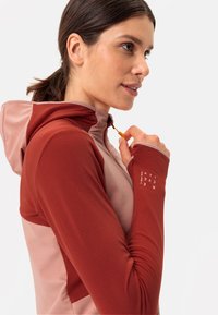 Sportliches Kapuzensweatshirt mit einem Farbblockdesign in Rost und Hellrosa, hergestellt aus einem strukturierten, feuchtigkeitsableitenden Stoff und mit Daumenlöchern.