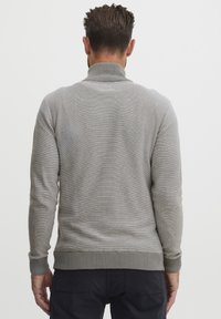 Grauer Strickpullover mit hohem Kragen, gerippten Bündchen und Saum, mit strukturiertem Finish und tailliertem Design. Schlichte Rückansicht.