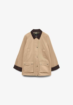 Smeđa jakna s okovratnikom od kordura, dva velika prednja džepa i kopčom na dugme. Ima opušteni kroj i duge rukave.