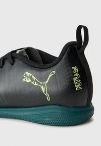Čierne a tyrkysové atletické tenisky Puma s neónovo zeleným logom Puma a textom "HRAJTE BEZ OBMEDZENÍ" na slučke na päte.