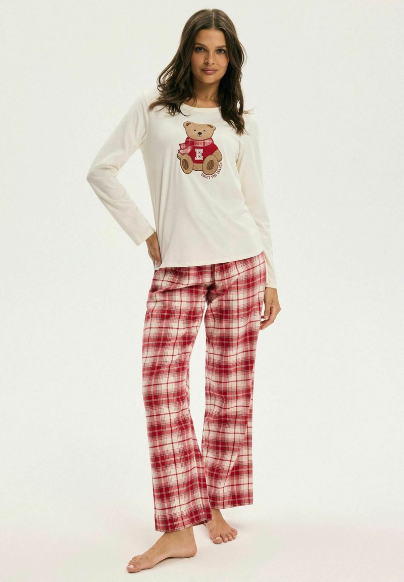 Biała piżama z długim rękawem z grafiką misia, w zestawie z czerwono-kremowymi spodniami w kratę. Miękki materiał, luźny krój, proste nogawki.