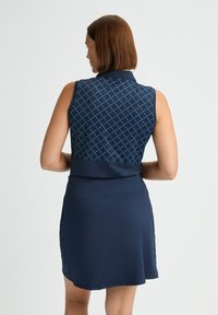 Vestido sin mangas de color azul marino con un diseño de cuello, que presenta un patrón de diamantes en la parte superior y una falda inferior sólida con detalles laterales.