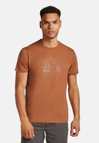 Braunes T-Shirt mit kurzen Ärmeln aus leichtem Stoff, das ein weißes Grafikdesign von Bäumen und einem Campingbus in einer Campingszene zeigt.