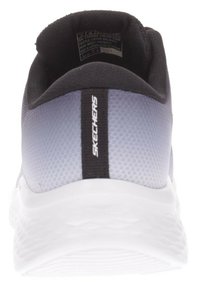 Zapatilla deportiva gris y negra con un upper texturizado, cuello acolchado y suela blanca con un patrón de olas. Nombre de la marca "SKECHERS" destacado.