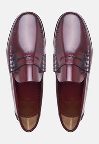 Bordeaux leren loafers met een gladde afwerking, voorzien van gedetailleerde stiksels en een verhoogd randontwerp op de bovenkant voor textuur.