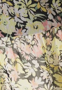 Schwarzer Stoff mit pastellgelbem, rosa und weißem Blumenmuster, mit geschichteter, leicht durchscheinender Textur und gerafften Nähten.