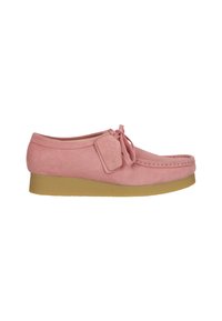 Scarpa in suede rosa con punta arrotondata, dettagli con lacci e suola in gomma beige. Presenta un piccolo etichetta di tessuto attaccata. Design semplice e lineare.