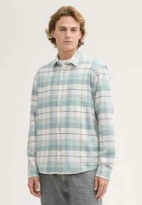 Hellblau kariertes Hemd aus weichem Stoff mit langen Ärmeln, Knopfleiste und abgerundetem Saum.