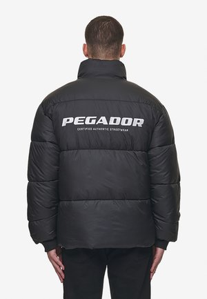 Giacca a vento nera con colletto alto, caratterizzata da trapuntatura orizzontale e cuciture a vista. Logo "PEGADOR" in bianco sulla schiena.
