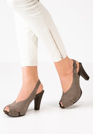 Grå ruskinds åbne slingback hæle med en høj sort hæl, der har dekorative sølvnitter langs kanterne og en spænde rem.