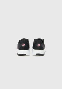 Baskets de sport noires avec une tige en maille, semelle intermédiaire blanche, logo rose prominent et design de talon texturé. Présente une pointe arrondie et une semelle extérieur noire.