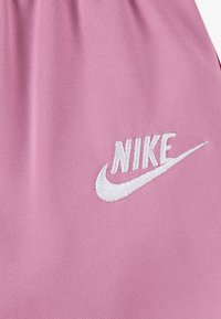 Nike rosa stoff med broderi av hvit logo. Teksturen er glatt, med en lett og pustende design.
