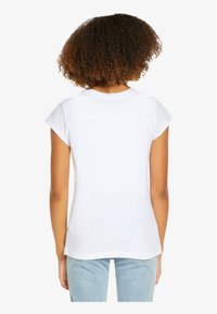 White cotton t-shirt with short cap sleeves and a rounded neckline. The back is plain with a smooth texture and tailored fit.