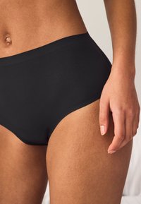 Czarne prążkowane figi typu hipster o fakturowanym wykończeniu. Wysoki stan, gładkie szwy oraz miękki materiał dopasowujący się do ciała.