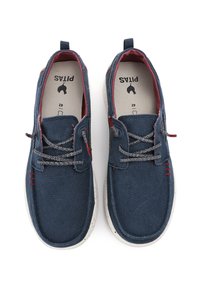 Zapatos de lona azul marino con acentos rojos, tejido texturizado, cordones grises y suelas salpicadas de blanco. Presentan una pestaña en el talón para facilitar su uso.