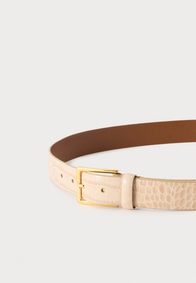 Ceinture beige à texture crocodile avec une boucle rectangulaire dorée et plusieurs trous sur un fond gris clair.