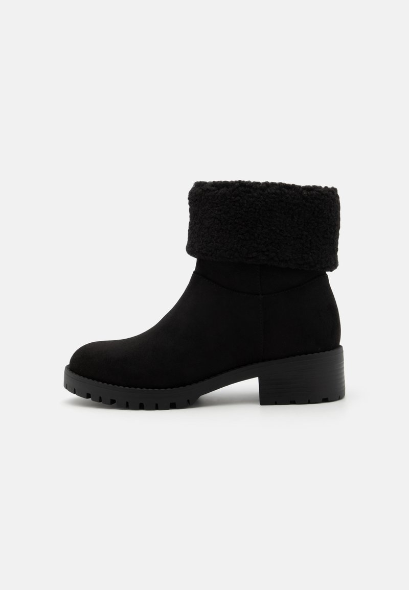Bottines noires en daim avec un revers en shearling pelucheux et une semelle en caoutchouc épais pour un meilleur grip et une stabilité accrue.