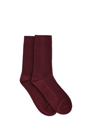 Chaussettes bordeaux avec un motif texturé et une section inférieure lisse. Conçues avec un bord-côte pour un maintien sécurisé. Fabriquées en matériau doux.