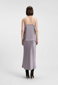 Lila satin camisol- och kjolset, med tunna axelband och en flytande silhuett. Tyget har en jämn textur, med slitsar på kjolen.
