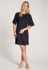 Navy blue dress with short flared sleeves, white polka dots, and a relaxed shape, made from soft fabric, reaching mid-thigh.