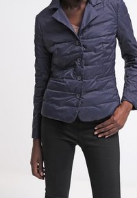 Námořnický prošívaný kabát s úzkým střihem, zapínáním na knoflíky a klopovým límcem. Obsahuje texturovanou tkaninu a jemný lesk.